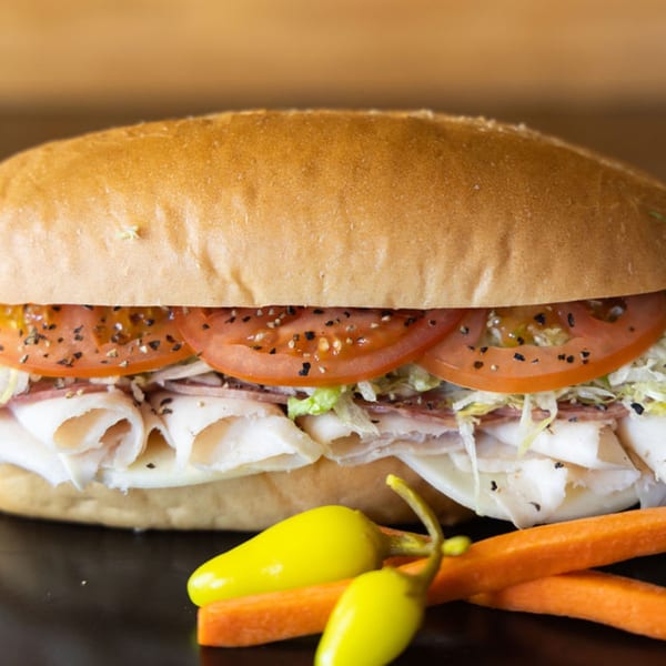 A Sub Station sandwich filled with sliced meats, cheese, lettuce, tomatoes, and black pepper.