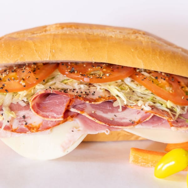 A Sub Station sandwich filled with deli meats, cheese, shredded lettuce, and sliced tomatoes.